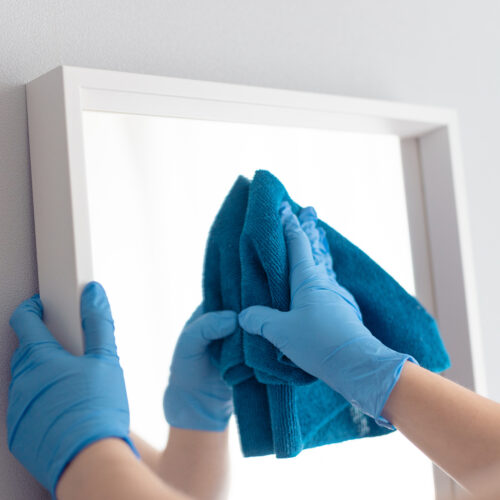 Woman cleaning mirror with rag. Housemaid cleaning at home